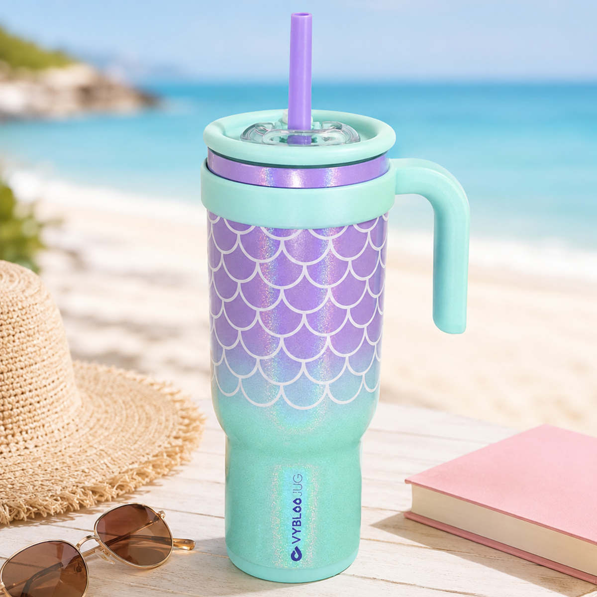 Taza marea azul VyblooJug en mesa de playa con sombrero y libro